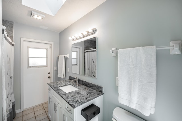 full bath featuring tile patterned flooring, toilet, a skylight, a shower with curtain, and vanity