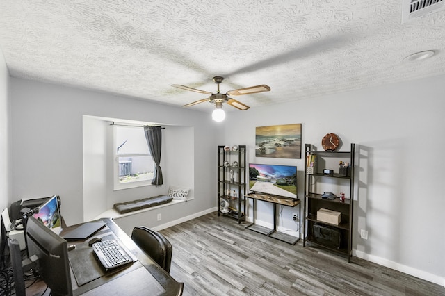 office space featuring visible vents, a ceiling fan, a textured ceiling, wood finished floors, and baseboards