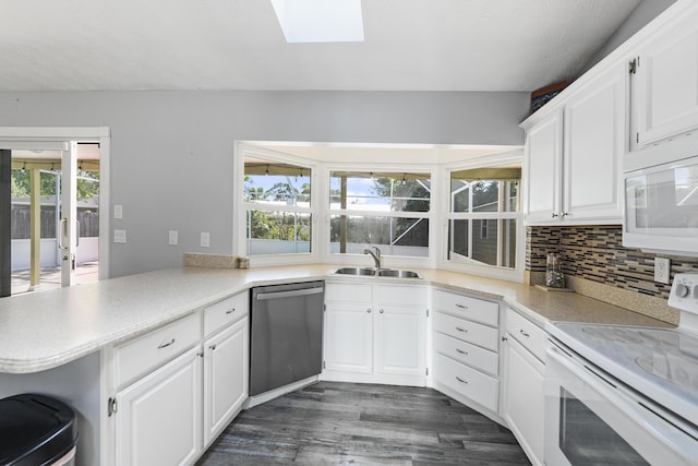 kitchen featuring a sink, white appliances, a peninsula, white cabinets, and decorative backsplash