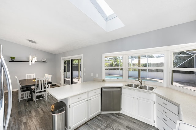 kitchen featuring lofted ceiling with skylight, appliances with stainless steel finishes, a peninsula, wood finished floors, and a sink