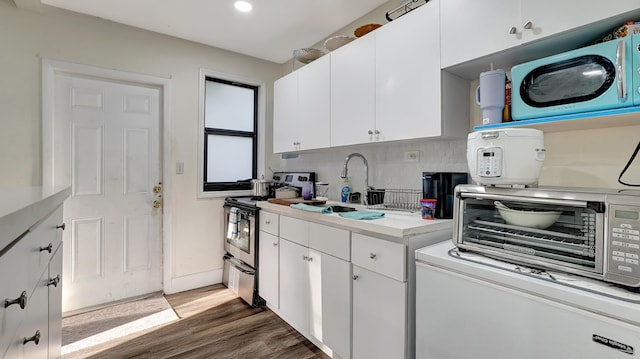 kitchen with light countertops, white cabinets, a sink, wood finished floors, and stainless steel range with electric stovetop