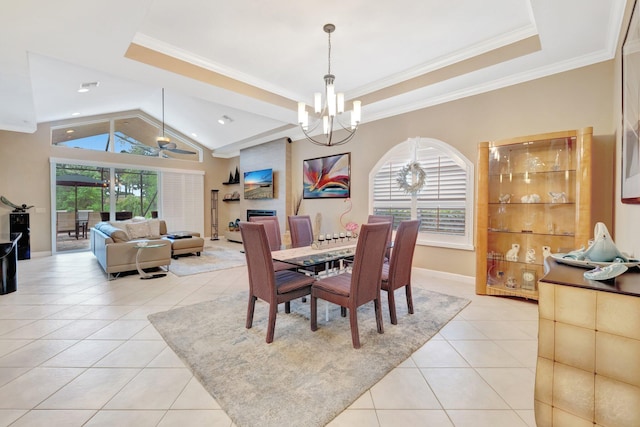 dining space featuring a tray ceiling, ornamental molding, vaulted ceiling, ceiling fan with notable chandelier, and light tile patterned flooring