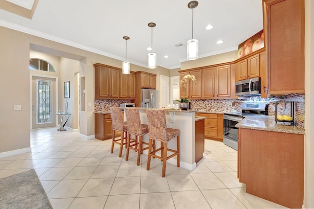 kitchen featuring light tile patterned floors, appliances with stainless steel finishes, a center island, and ornamental molding