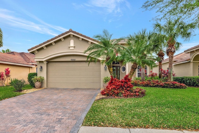 mediterranean / spanish home with stucco siding, driveway, a front yard, an attached garage, and a tiled roof