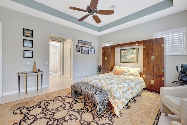 bedroom featuring visible vents, a ceiling fan, a raised ceiling, and baseboards