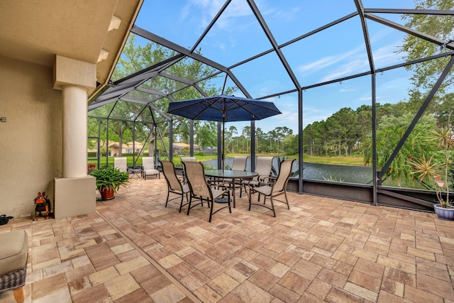 view of patio with outdoor dining area, a water view, and a lanai