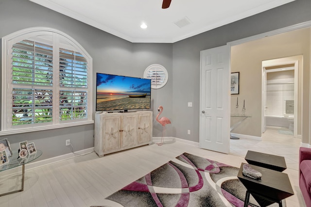 living room with visible vents, baseboards, crown molding, and light wood finished floors