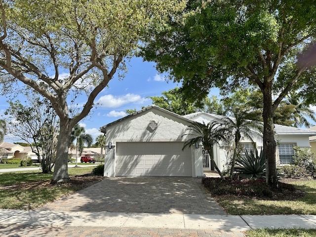 ranch-style house featuring decorative driveway, an attached garage, and stucco siding