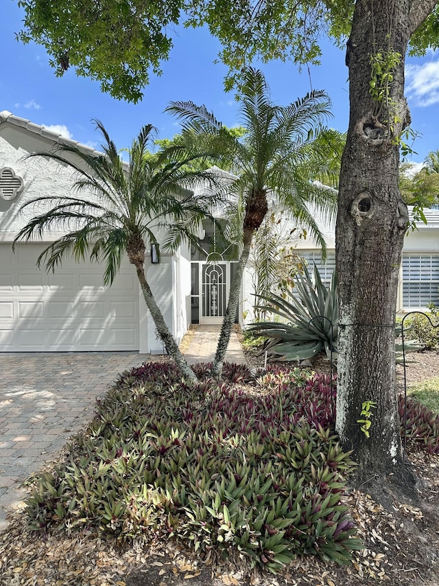 view of front of house featuring an attached garage, decorative driveway, and stucco siding