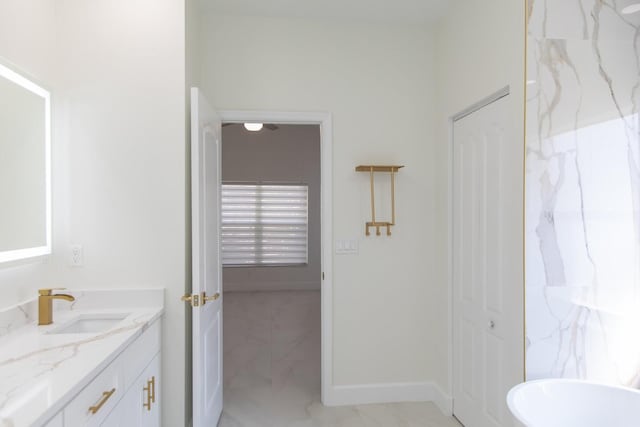bathroom with vanity, a soaking tub, baseboards, and marble finish floor