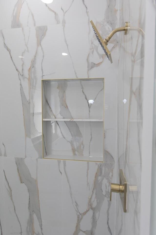 interior details featuring a marble finish shower