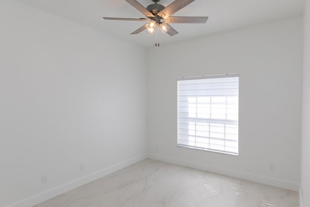 empty room with marble finish floor, baseboards, and ceiling fan