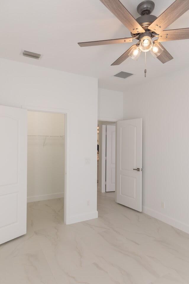 unfurnished bedroom with visible vents, marble finish floor, a closet, baseboards, and a spacious closet