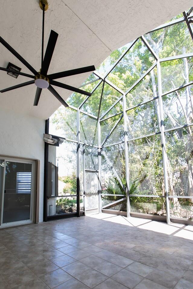 view of patio / terrace featuring glass enclosure and a ceiling fan