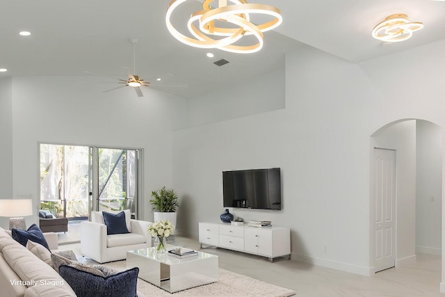 living area with baseboards, recessed lighting, arched walkways, a towering ceiling, and ceiling fan with notable chandelier