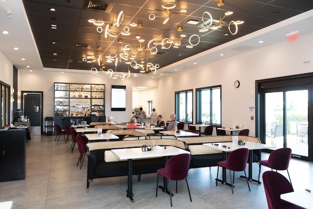 dining room with a raised ceiling, a notable chandelier, visible vents, and plenty of natural light
