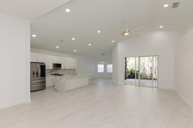 kitchen with visible vents, open floor plan, white cabinets, stainless steel appliances, and a ceiling fan
