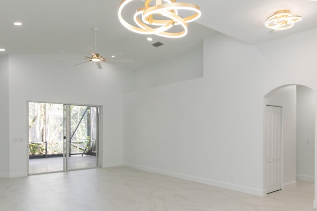 empty room with arched walkways, recessed lighting, ceiling fan with notable chandelier, and baseboards