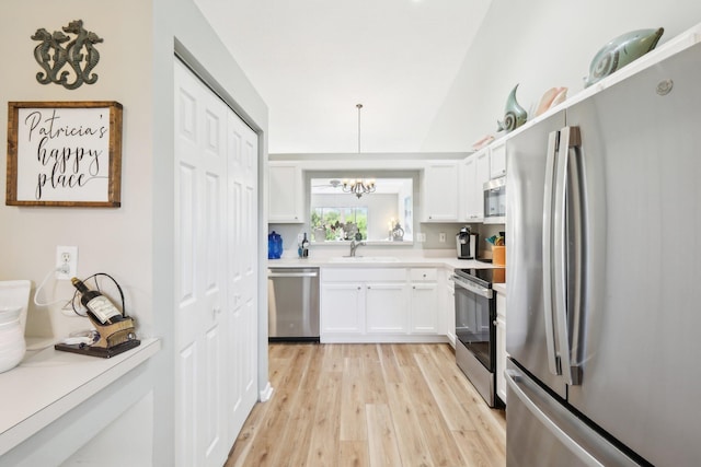 kitchen featuring light wood-style flooring, a sink, white cabinets, light countertops, and appliances with stainless steel finishes