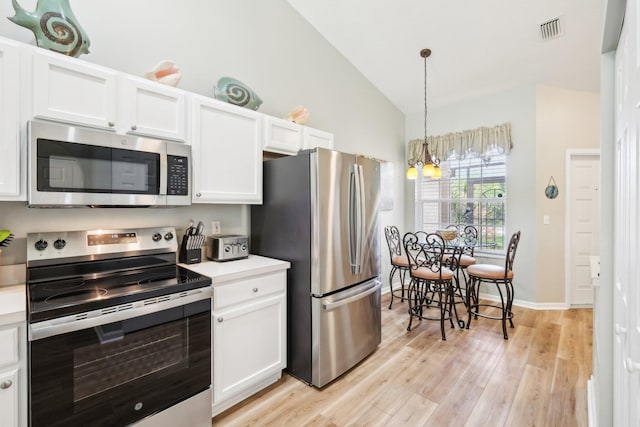 kitchen with stainless steel appliances, white cabinets, visible vents, and vaulted ceiling