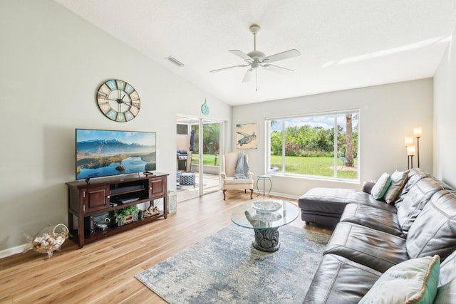 living room with baseboards, visible vents, a ceiling fan, light wood-style flooring, and vaulted ceiling