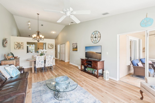 living area featuring vaulted ceiling, ceiling fan with notable chandelier, arched walkways, and light wood-style flooring