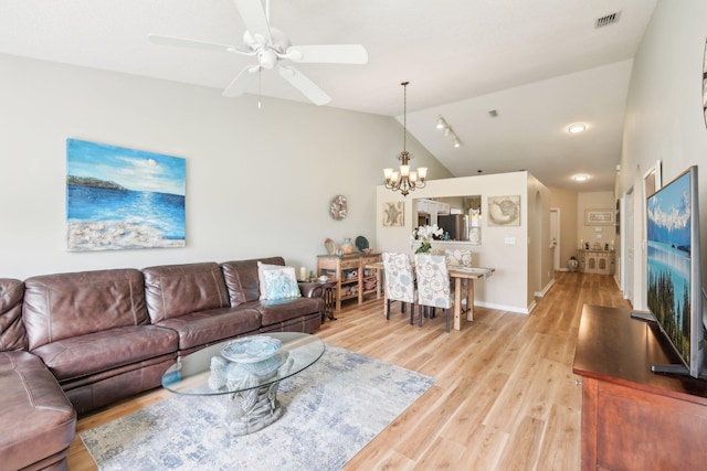 living room with visible vents, baseboards, lofted ceiling, light wood-type flooring, and ceiling fan with notable chandelier