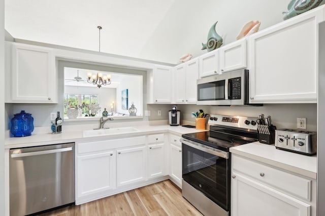 kitchen featuring stainless steel appliances, an inviting chandelier, a sink, and white cabinets