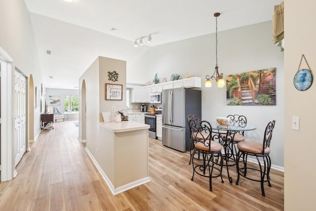 kitchen with appliances with stainless steel finishes, light countertops, high vaulted ceiling, and light wood-style flooring