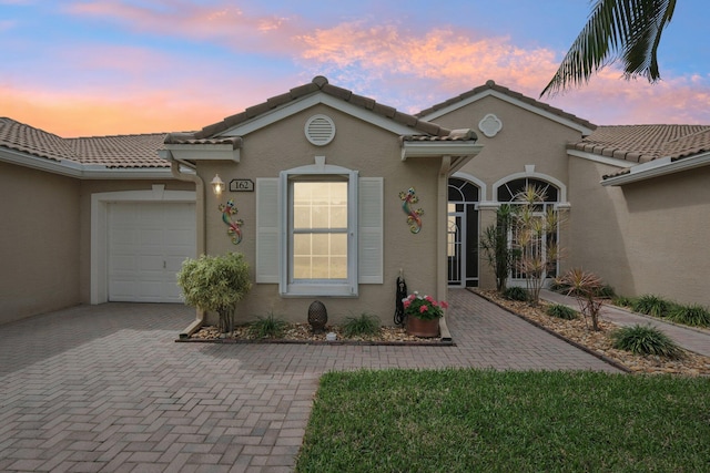 mediterranean / spanish-style house featuring a garage, decorative driveway, and stucco siding