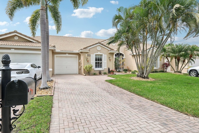 mediterranean / spanish home with decorative driveway, stucco siding, an attached garage, a front yard, and a tiled roof