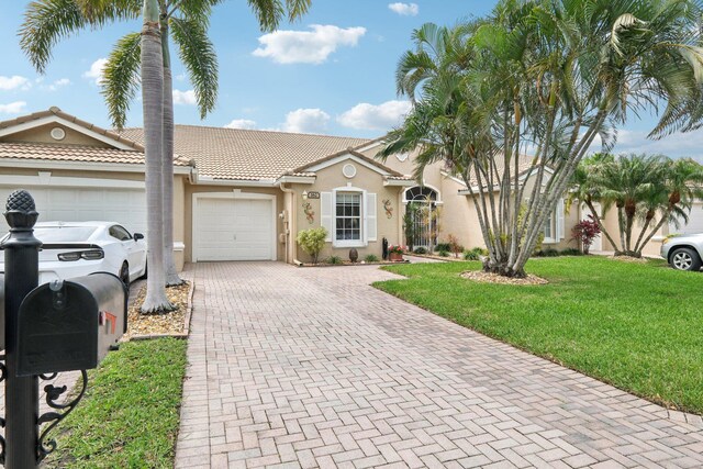 view of front of house featuring an attached garage, a tiled roof, decorative driveway, and stucco siding