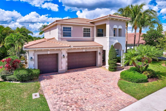 mediterranean / spanish house with decorative driveway, a tile roof, and stucco siding