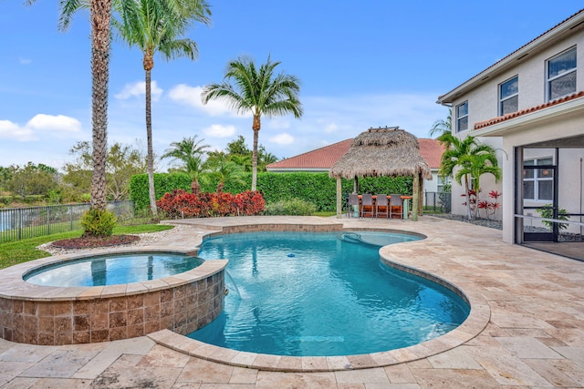 view of pool featuring fence, a pool with connected hot tub, outdoor dry bar, a gazebo, and a patio area