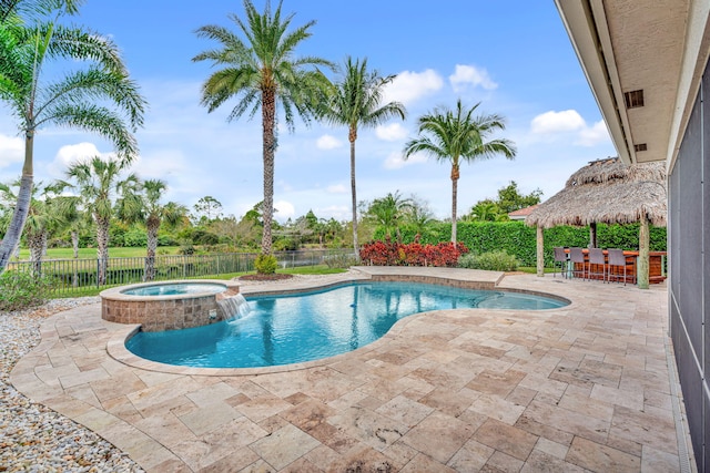 view of swimming pool with a pool with connected hot tub, fence, outdoor dry bar, and a patio