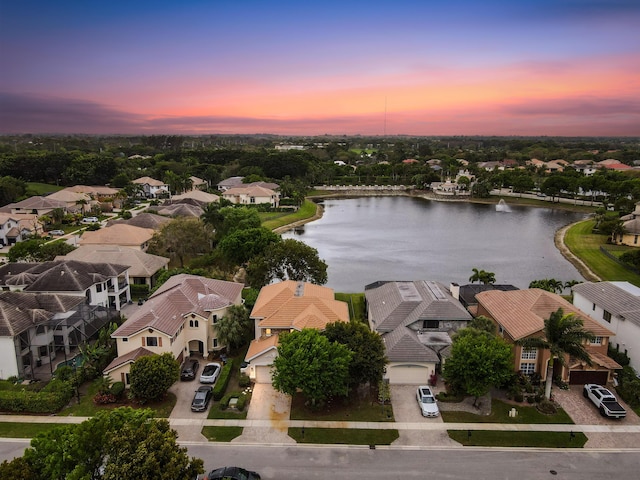 aerial view at dusk featuring a water view and a residential view