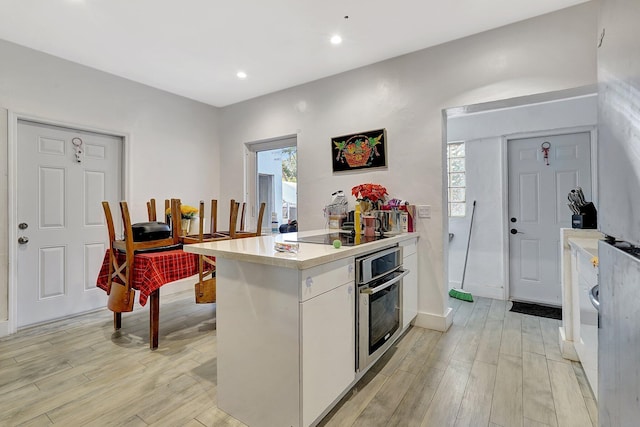 kitchen featuring a peninsula, light countertops, oven, and light wood-style floors