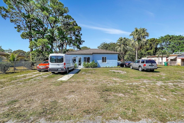 view of front of property with french doors, stucco siding, a front yard, fence, and a tiled roof