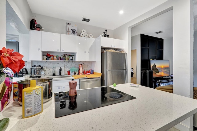 kitchen with stainless steel appliances, decorative backsplash, visible vents, and white cabinetry