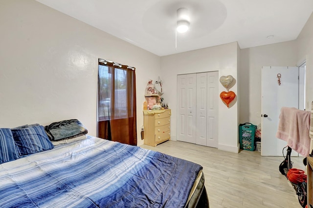 bedroom featuring baseboards, light wood-style flooring, a ceiling fan, and a closet