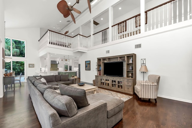 living area featuring baseboards, visible vents, wood finished floors, ceiling fan, and high vaulted ceiling