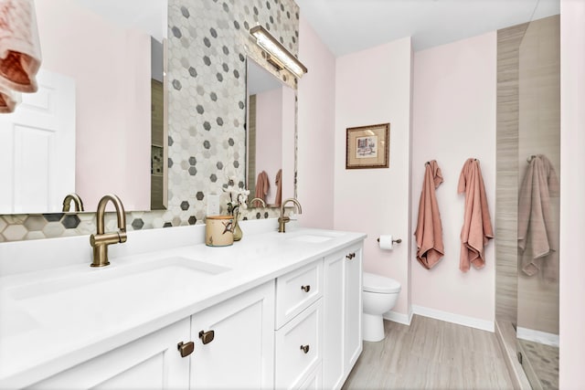 bathroom with double vanity, toilet, baseboards, and a sink