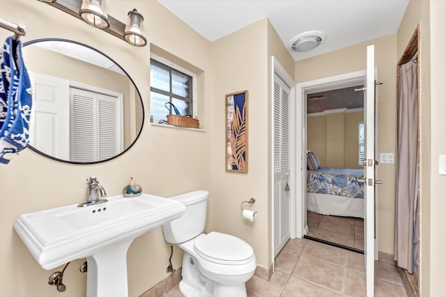 ensuite bathroom with toilet, ensuite bathroom, a closet, baseboards, and visible vents