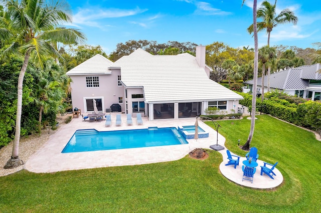 view of pool with a sunroom, a yard, a pool with connected hot tub, and a patio
