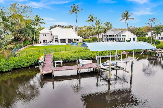 dock area featuring a fenced backyard, boat lift, a lawn, and a water view
