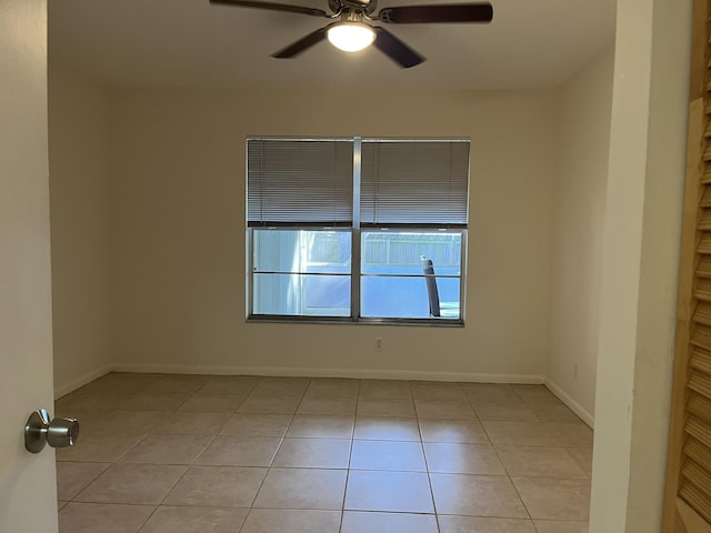 empty room featuring light tile patterned floors, a ceiling fan, and baseboards