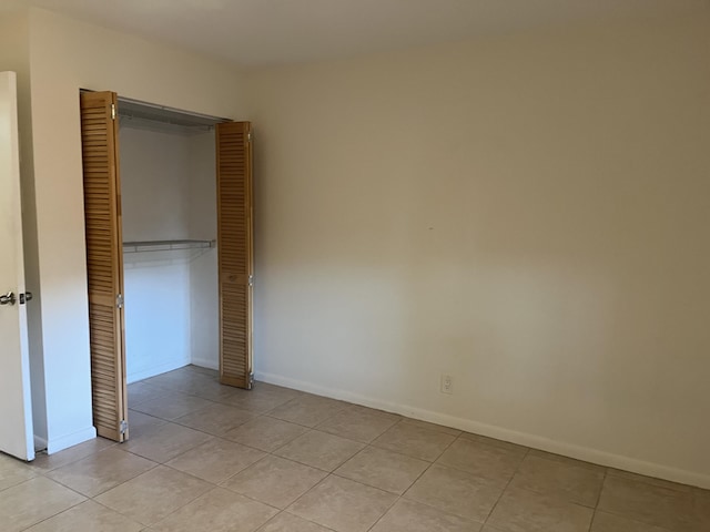 unfurnished bedroom with a closet, baseboards, and light tile patterned floors