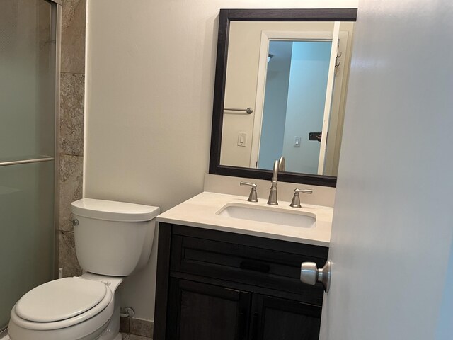 bathroom with toilet, a shower with shower door, and vanity