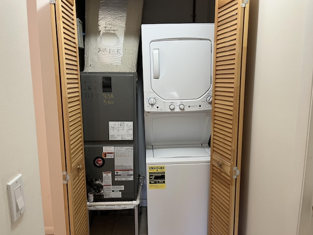 clothes washing area featuring laundry area, stacked washer / dryer, and tile patterned floors