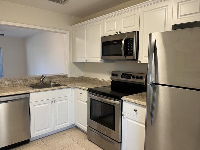 kitchen featuring light tile patterned floors, light countertops, appliances with stainless steel finishes, white cabinets, and a sink